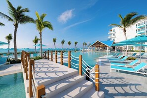 A resort pool area with clear blue water, palm trees, and lounge chairs. - Margaritaville Island Reserve Riviera Maya (Puerto Morelos)
