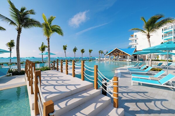 A resort pool area with clear blue water, palm trees, and lounge chairs. - Margaritaville Island Reserve Riviera Maya (Puerto Morelos)