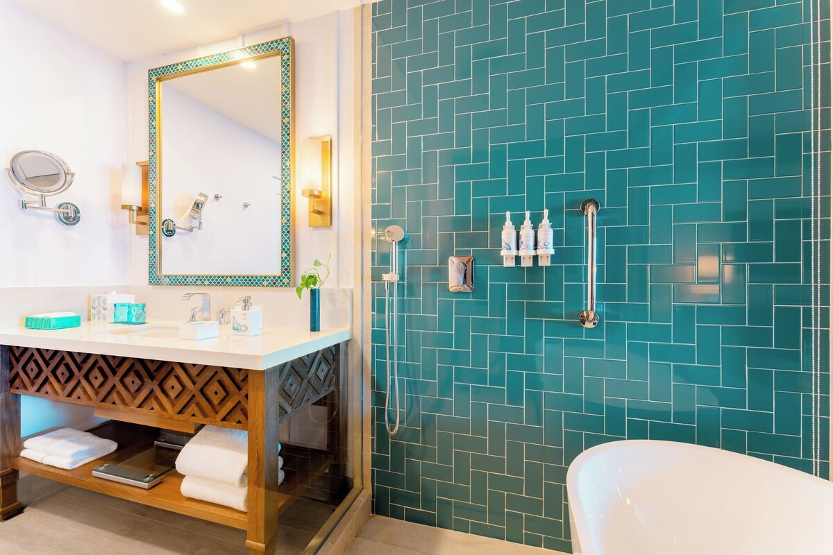 Une salle de bain avec un lavabo blanc, un miroir, une douche avec un pommeau de douche amovible et une baignoire.