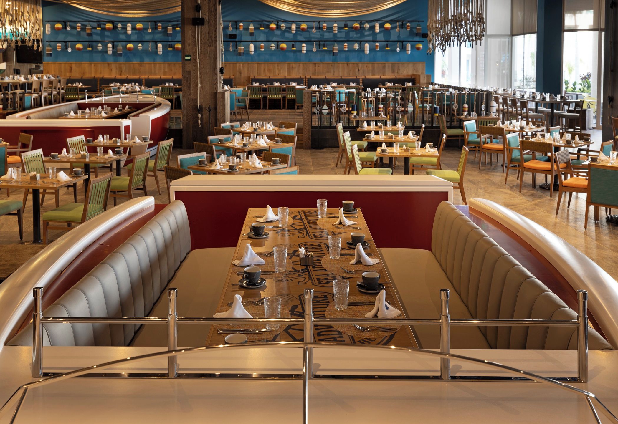 Un restaurant spacieux doté de plusieurs espaces de restauration, notamment un espace central avec une table haute et des banquettes de chaque côté.