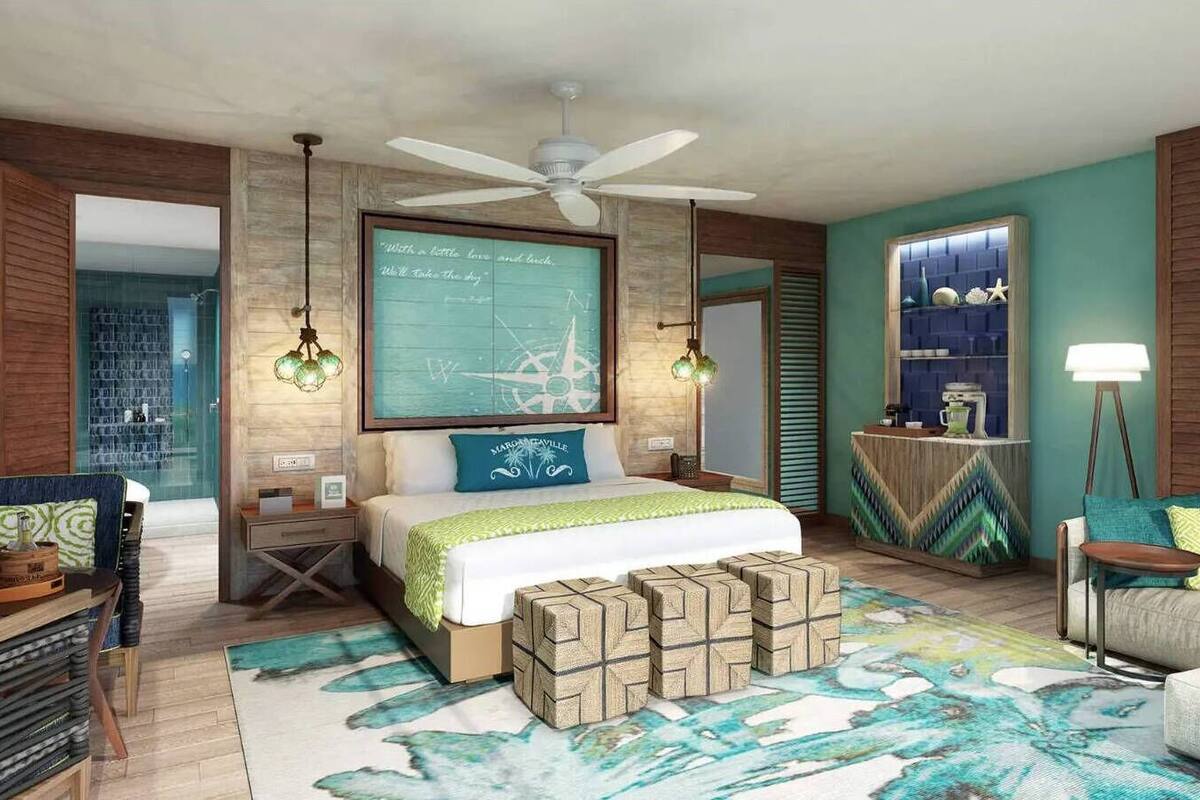 A bedroom with a bed, a ceiling fan, a wall clock, a bedside table, a nightstand, a lamp, and a rug.