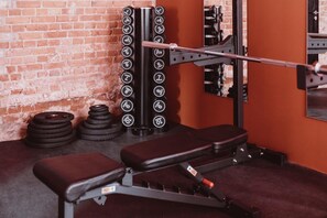 Un gimnasio con una prensa de banca, discos de pesas y una estructura para sentadillas.
