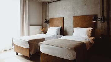 A hotel room with two beds, a concrete wall, and a radiator.