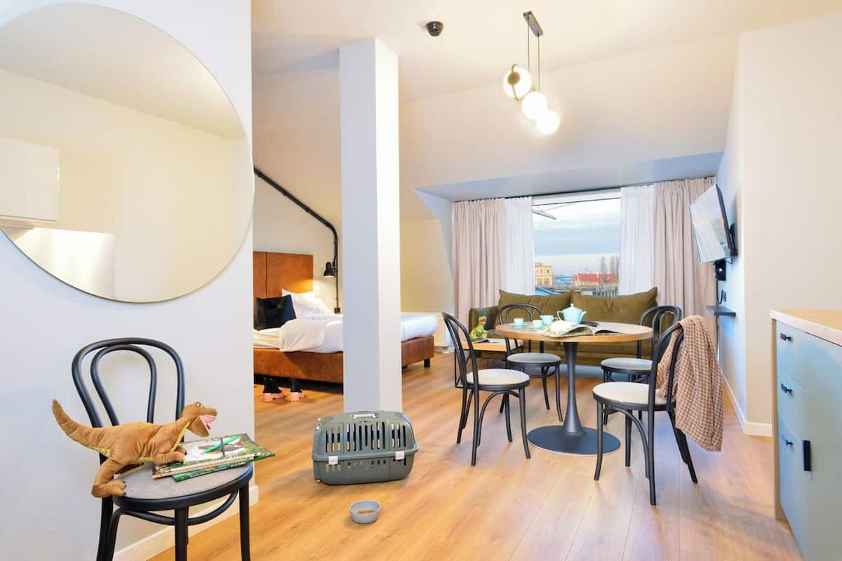 A modern, compact living space with a dining area, a bed, and a view of the city.