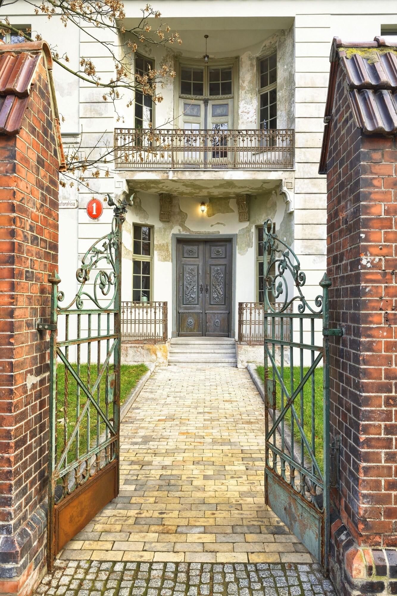 A two-story building with a central entrance featuring a double door and a small balcony above.