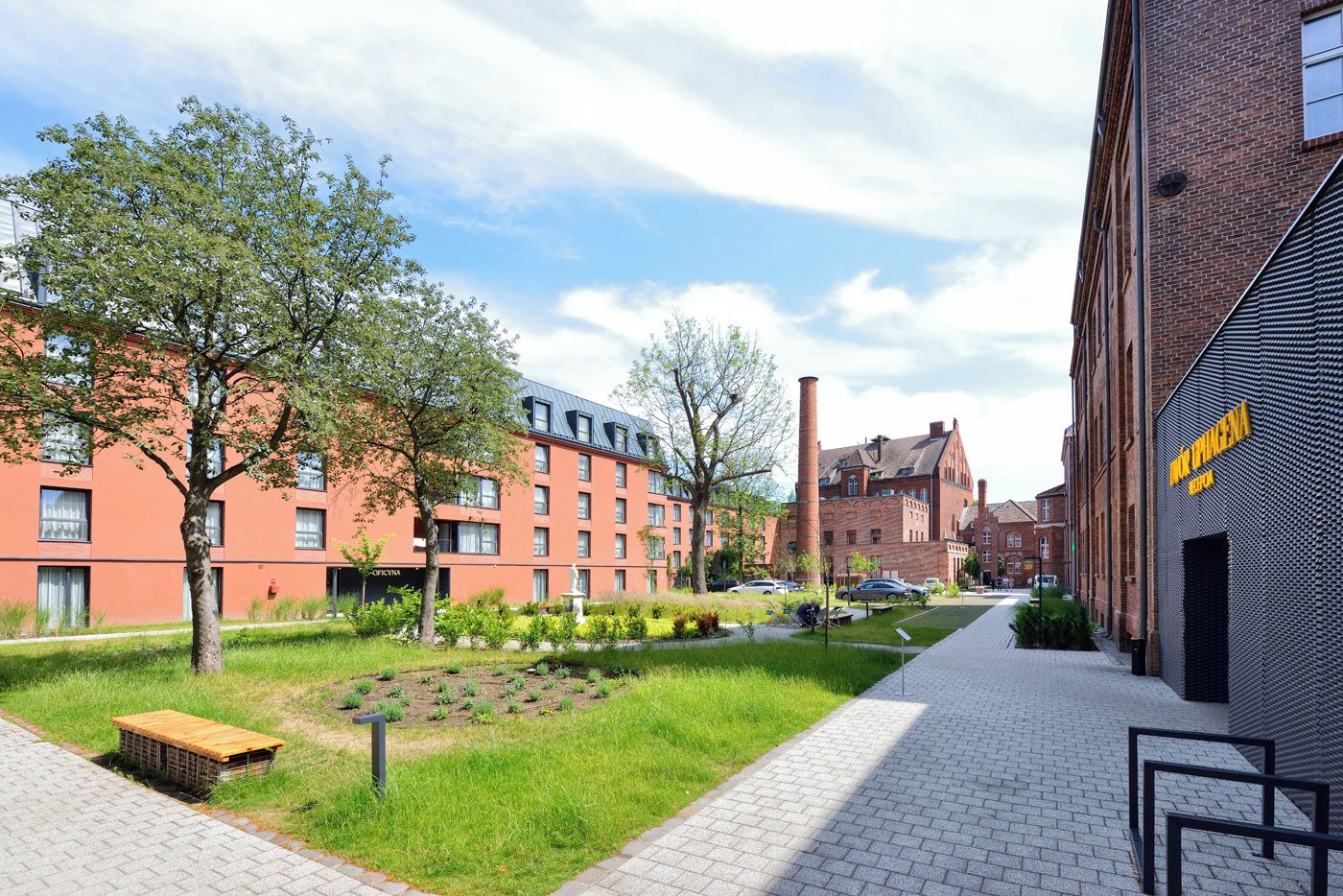 A courtyard with a brick building, a grassy area, and a paved walkway.