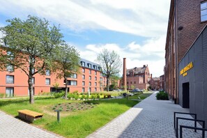 Un patio con un edificio de ladrillo, una zona con césped y un sendero empedrado.
