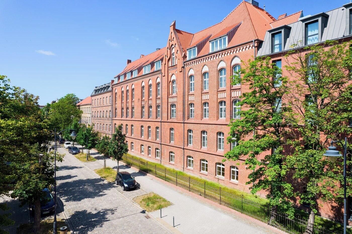 A large red brick building with multiple windows and a sloped roof.