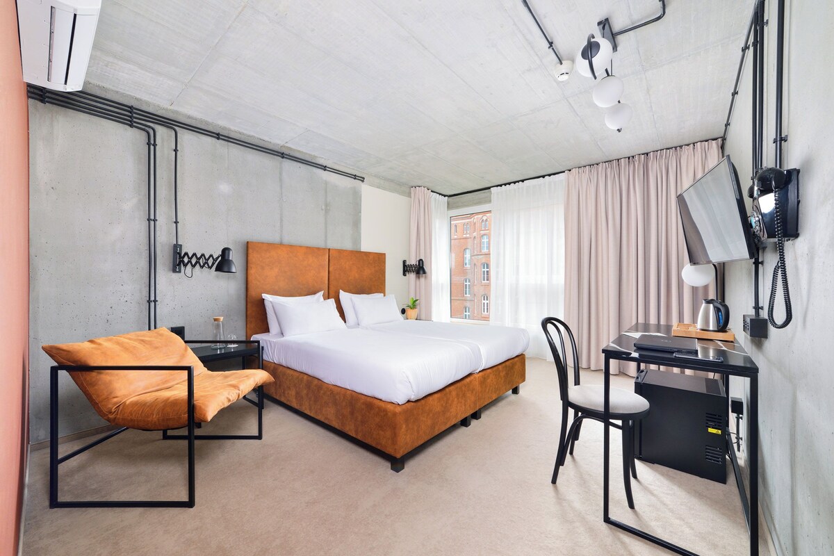 Una habitación de hotel moderna con una cama grande, un escritorio, una silla y un televisor.