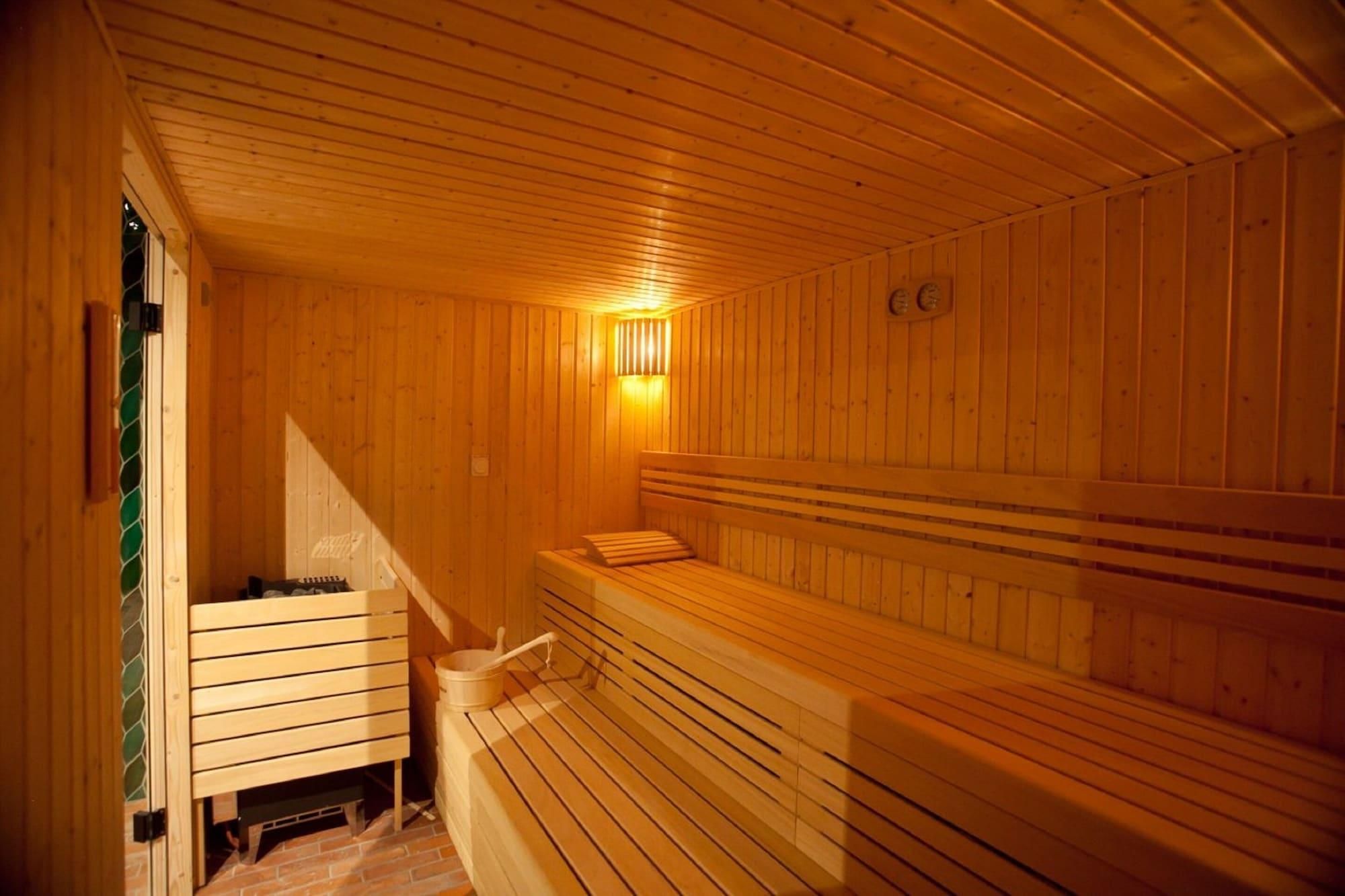 A wooden sauna with benches and a wall-mounted heater.