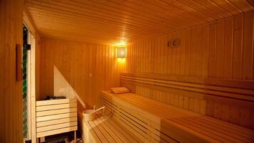 A wooden sauna with benches and a wall-mounted heater.
