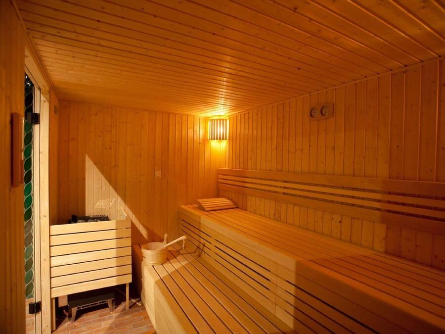 A wooden sauna with benches and a wall-mounted heater.
