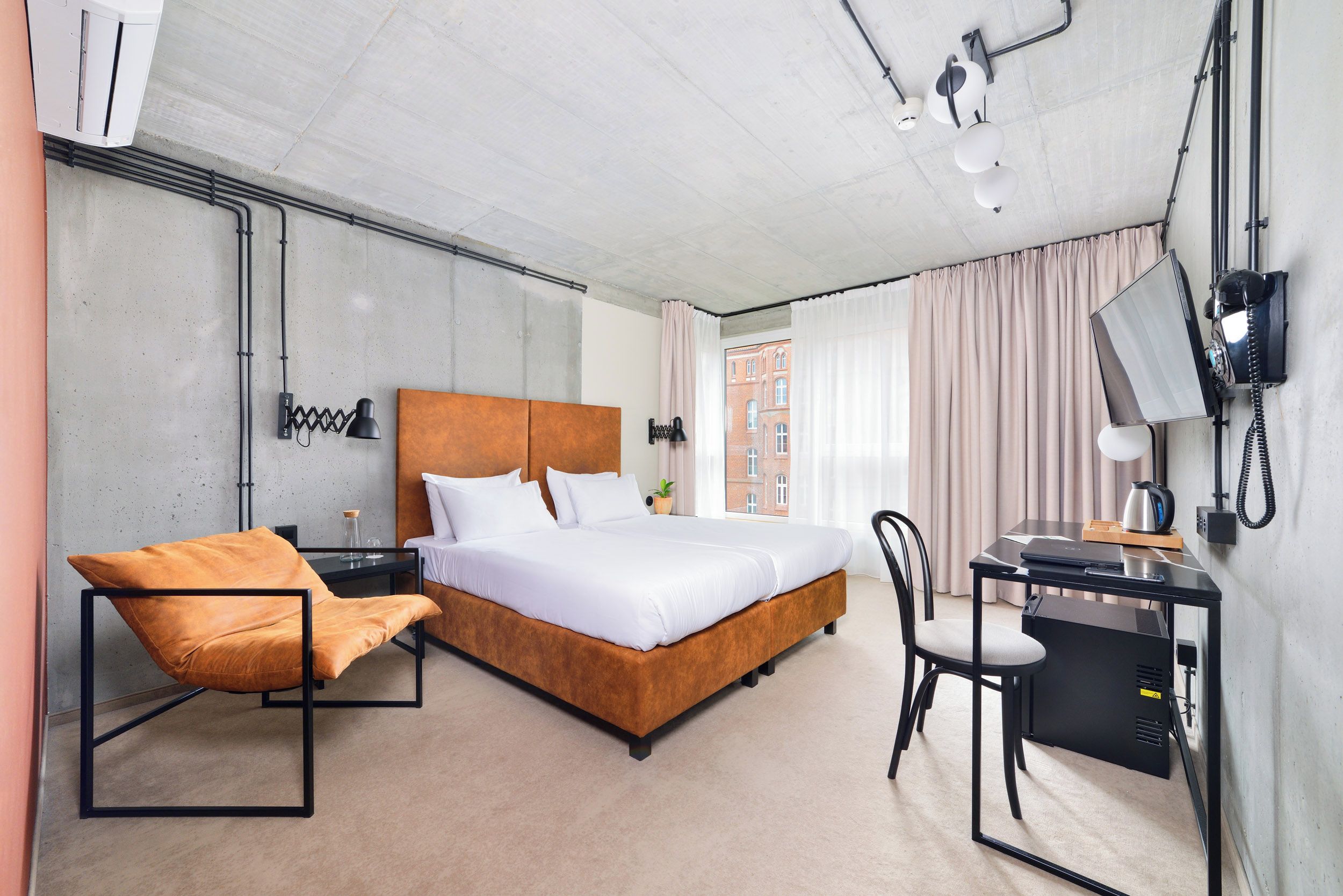 A modern hotel room with a large bed, a desk, a chair, and a TV.