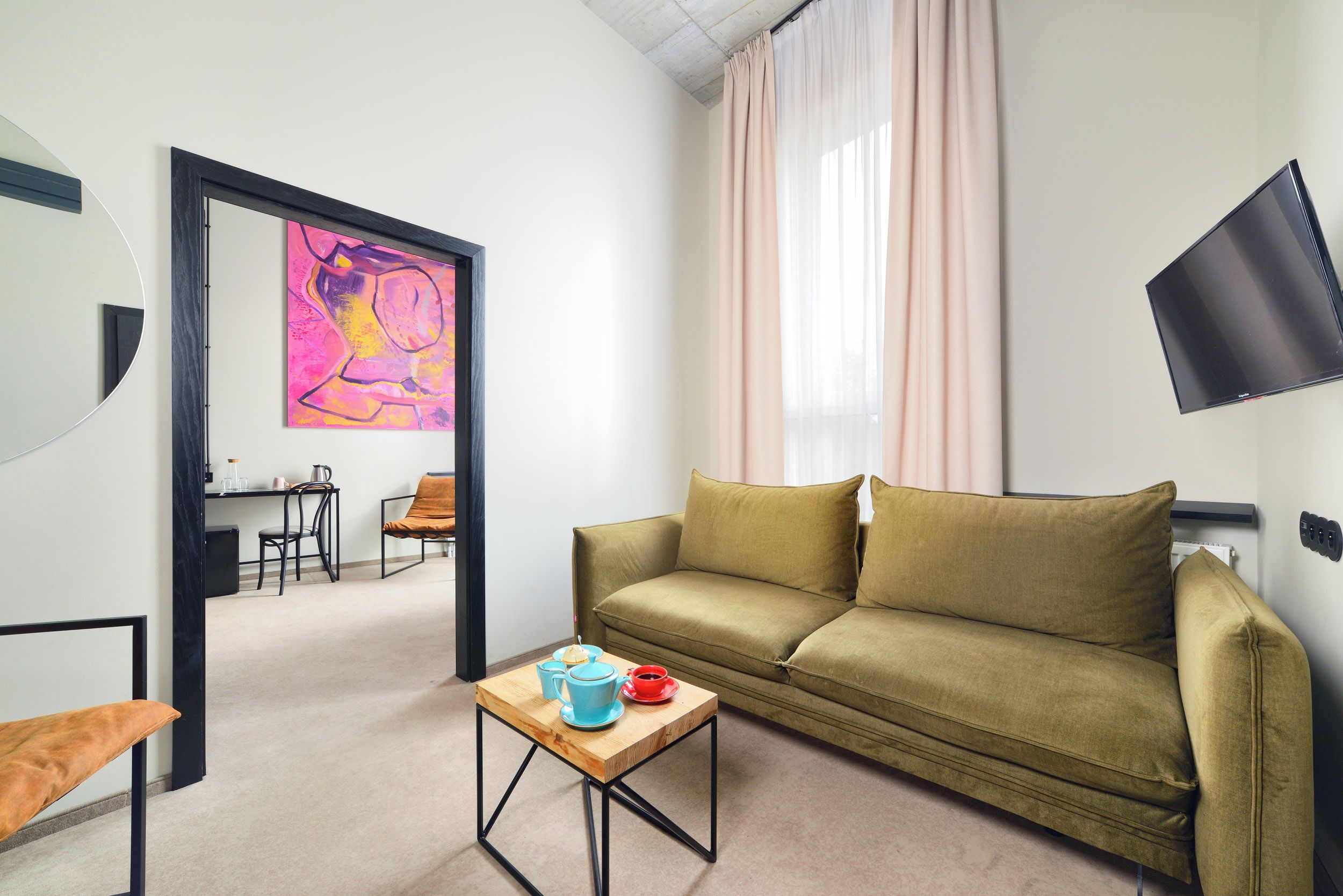A modern living room with a sofa, a coffee table, a TV, and a painting on the wall.