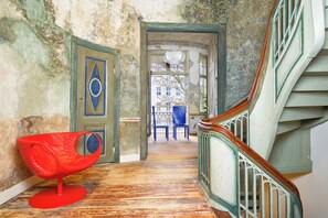 A wooden staircase with a green railing, a red chair, and a door with a blue and gold design. - Dwor Uphagena Arche Gdańsk (Gdańsk)