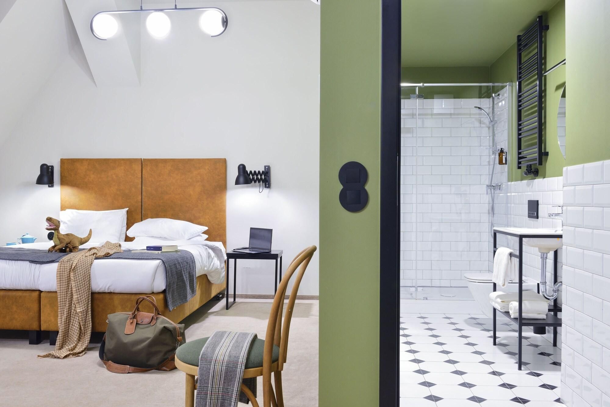 A bedroom with a bed, bedside lamp, and a small desk with a laptop.