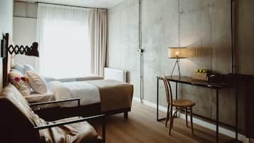 A modern hotel room with a bed, a desk, a chair, and a lamp.