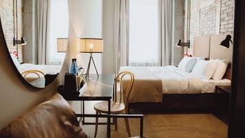 Una habitación de hotel con una cama, un escritorio, una silla, una lámpara y un espejo grande.