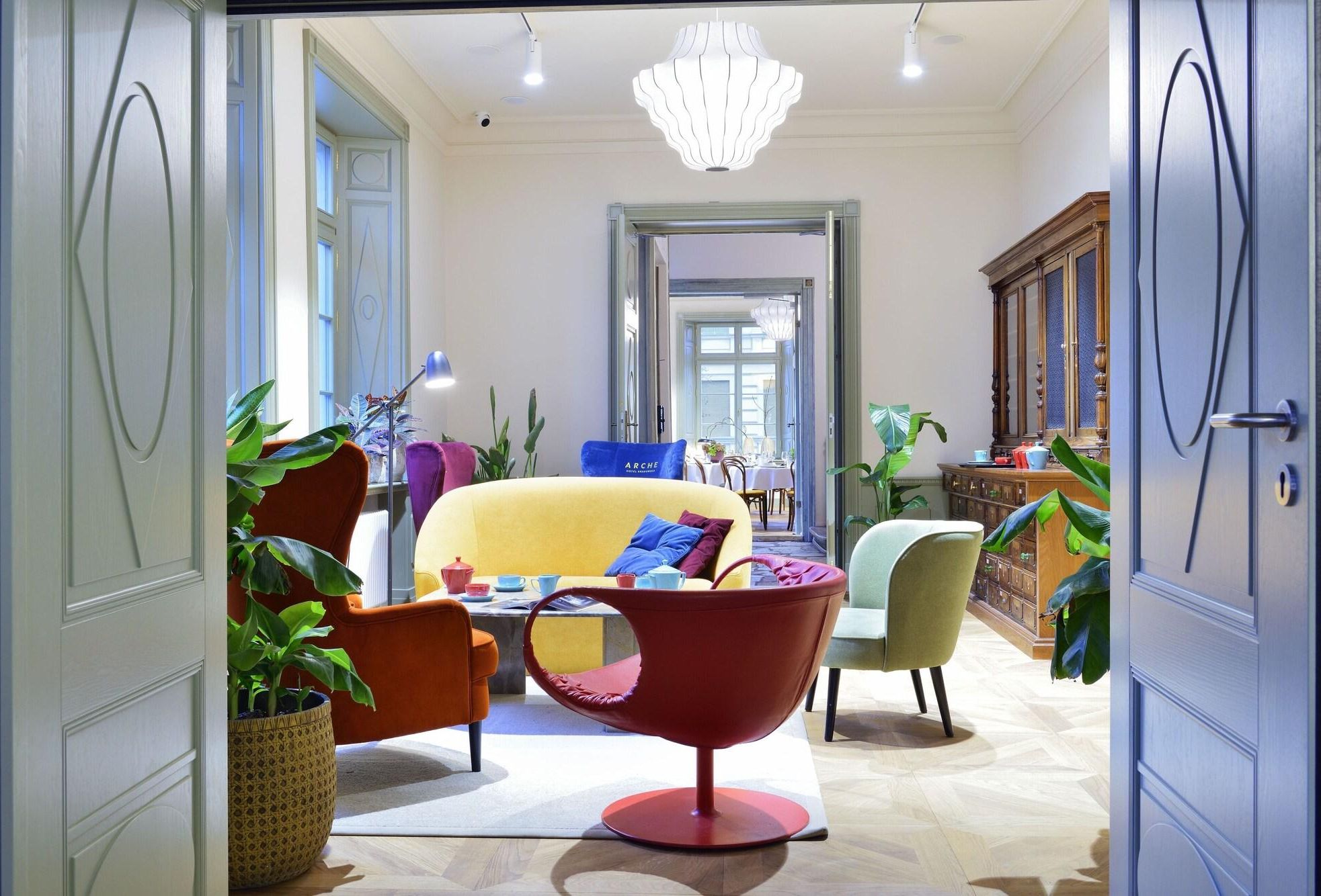 A spacious living room with a yellow sofa, red armchair, and a dining area in the background.