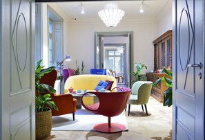 Amplio salón con un sofá amarillo, un sillón rojo y un comedor al fondo.