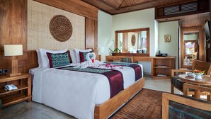 A spacious bedroom with a large bed, wooden headboard, and a decorative wall panel. - Sakti Garden Resort & Spa (Ubud)