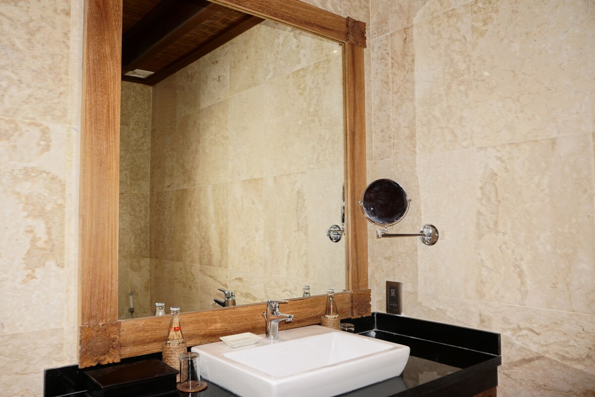 A bathroom with a large mirror, a white sink, and a black countertop.