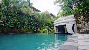 A swimming pool surrounded by lush greenery and a stone structure. - Sakti Garden Resort & Spa (Ubud)