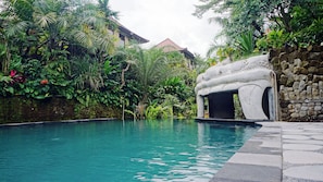 A swimming pool surrounded by lush greenery and a stone structure. - Sakti Garden Resort & Spa (Ubud)