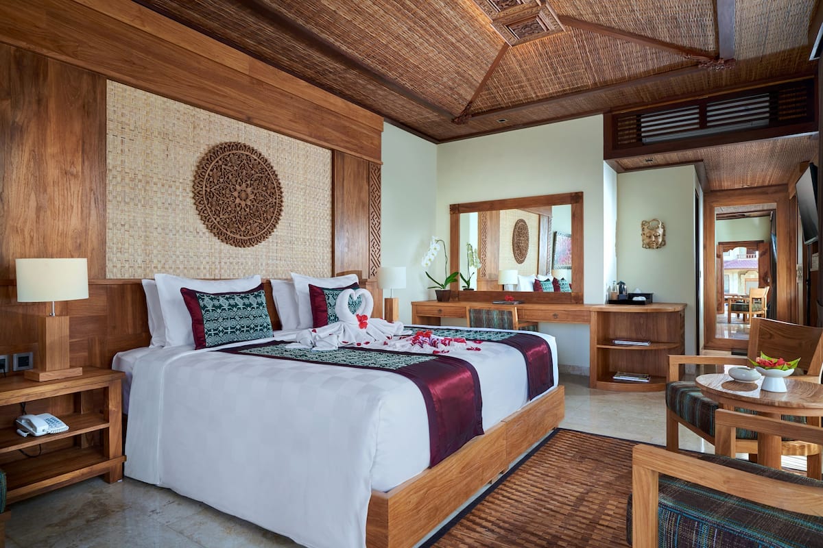 A spacious bedroom with a large bed, wooden headboard, and a woven wall hanging.