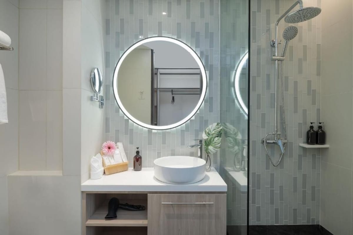 A modern bathroom with a round mirror, a sink, and a shower.