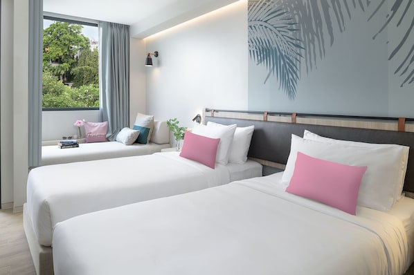 A hotel room with two beds, a large window with curtains, a wall-mounted lamp, and a tropical leaf artwork. - Jonox Phuket Karon (Karon)