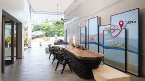 A modern reception area with a wooden reception desk, black chairs, and a glass wall with a map design. - Jonox Phuket Karon (Karon)