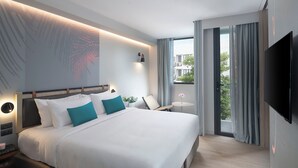 A modern hotel room with a large bed, a bedside table, a chair, a small table with a vase, and a TV. - Jonox Phuket Karon (Karon)