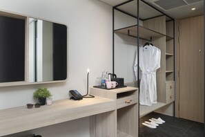 Une salle de bain moderne avec un meuble-lavabo en bois, un miroir, un évier, une petite plante, un téléphone et un peignoir suspendu à un porte-serviettes.