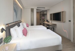 A modern hotel room with a large bed, bedside table, lamp, and a desk area with a mirror and television. - Jonox Phuket Karon (Karon)