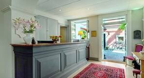 A modern kitchen with a marble countertop, a vase of flowers, and a view of the outdoor area. - Hotel Cannero (Cannero Riviera)
