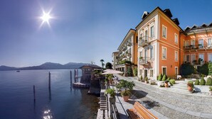A waterfront hotel with outdoor seating and a view of the lake. - Hotel Cannero (Cannero Riviera)