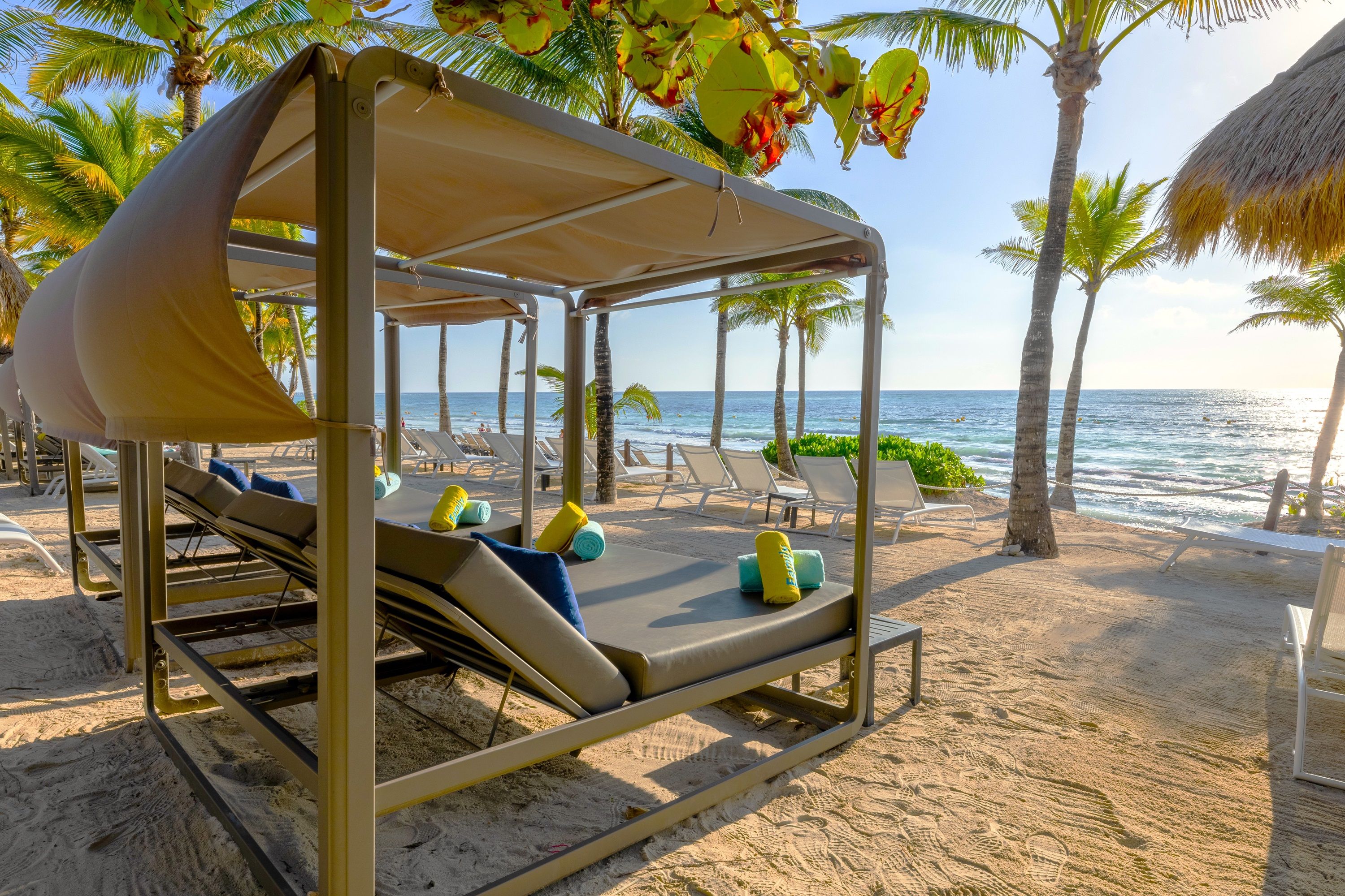 Uma cabana de praia com toldo, cadeiras de descanso e almofadas.
