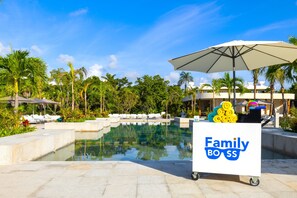 Ein Poolbereich mit Liegestühlen, einem Wasserspiel und einem Wagen mit der Aufschrift 'Family Boss'.