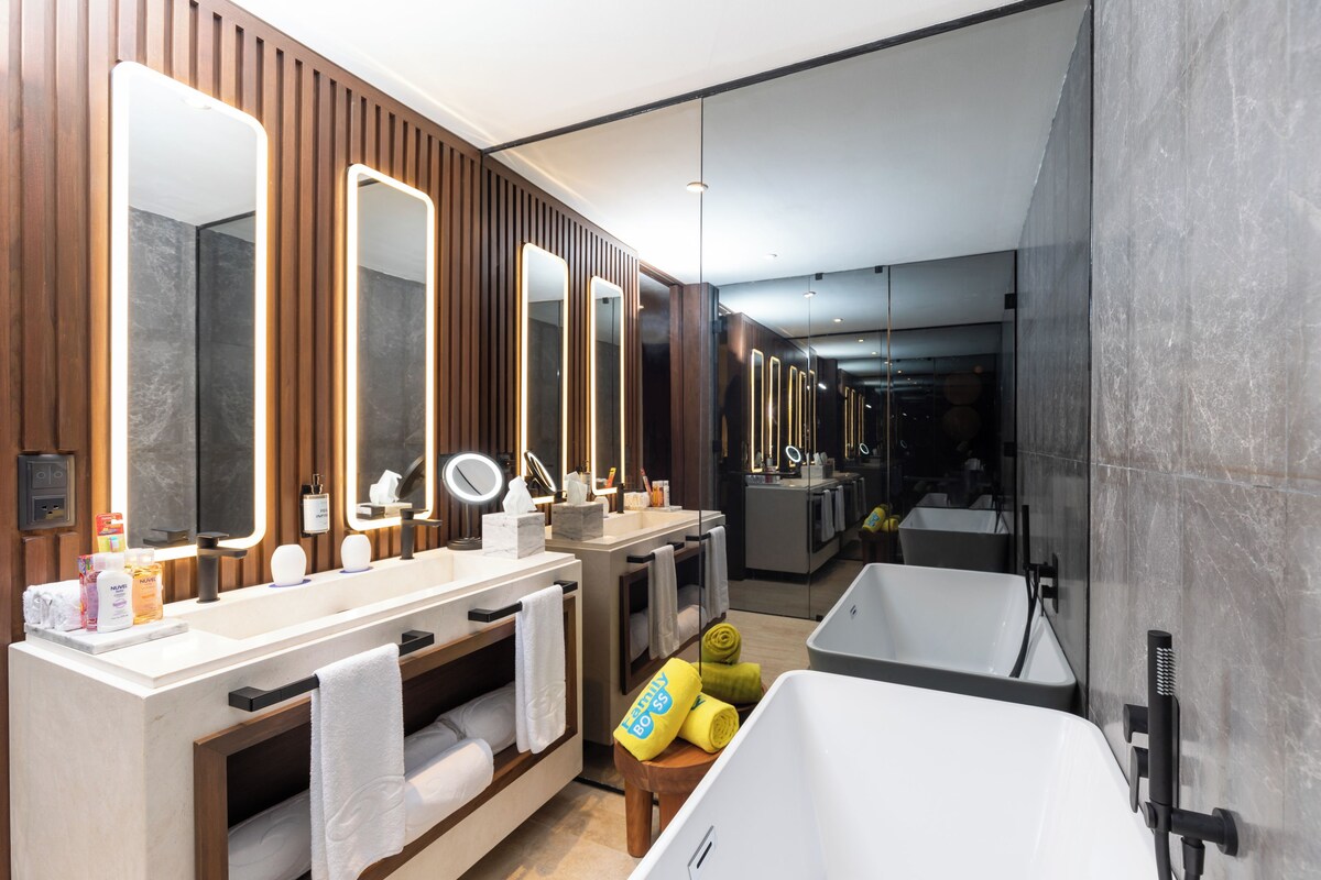 Une salle de bain moderne avec un grand miroir, un meuble-lavabo et une baignoire.