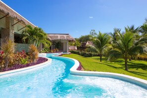 Una piscina de diseño curvo, rodeada de abundante vegetación y palmeras.