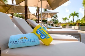Zona de piscina con sillones y sombrillas.