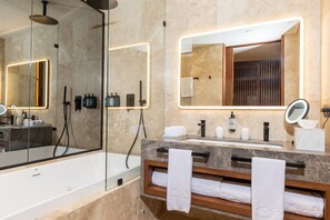 Une salle de bain moderne avec une douche en verre, un grand miroir et un meuble-lavabo doté d’un plan de travail en marbre.