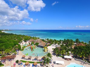 Un complexe hôtelier doté d’une piscine, de palmiers et d’une plage.