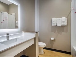 Un baño moderno con un lavabo blanco, un espejo, un inodoro y un perchero con toallas.