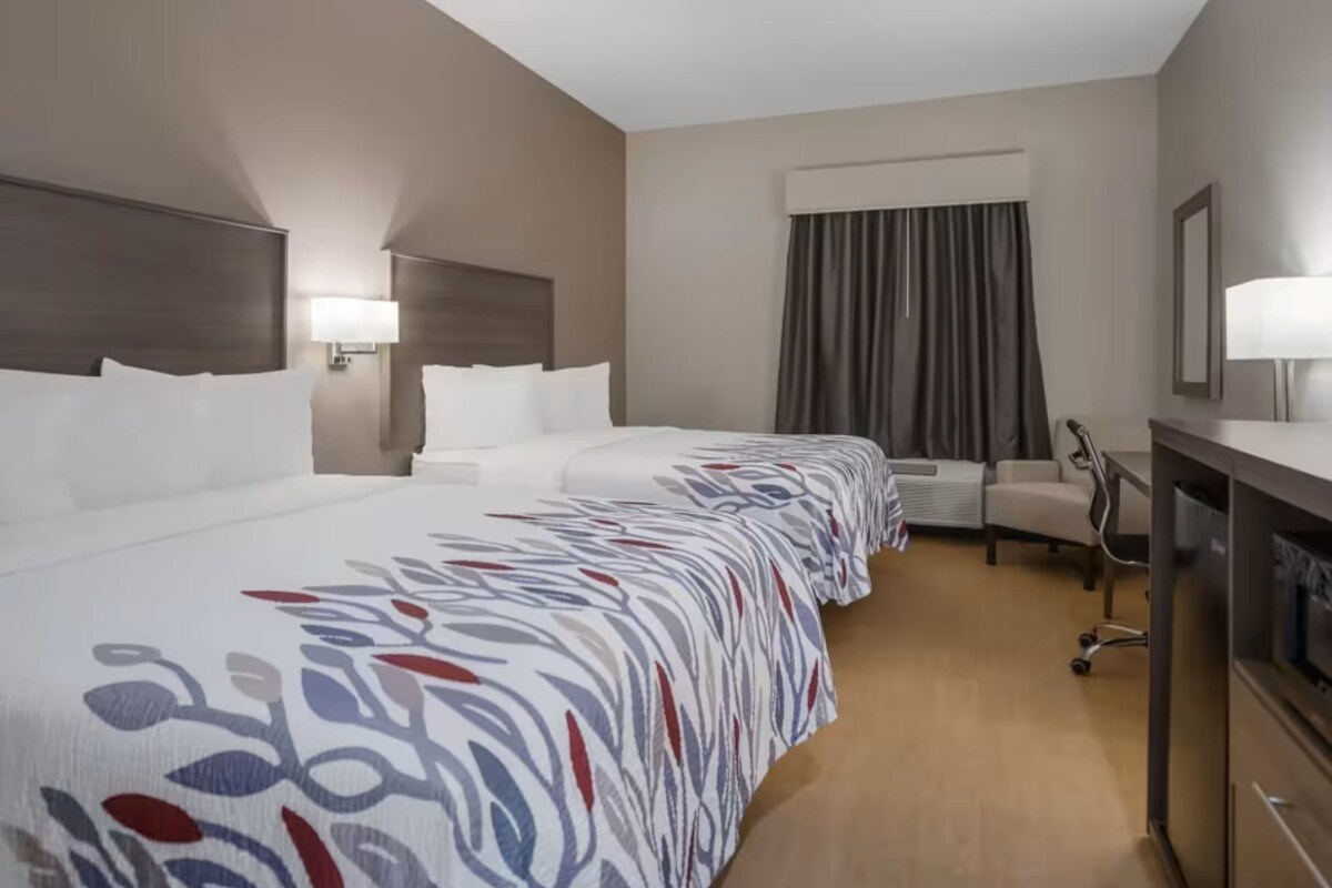 Una habitación de hotel con una cama grande, un escritorio, una silla y un equipo de aire acondicionado.