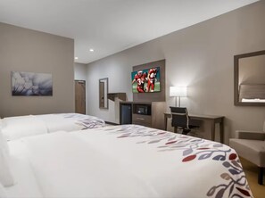 Una habitación de hotel con dos camas, un escritorio, un televisor y un cuadro en la pared.