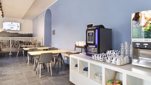 Una cafetería moderna con una máquina de café, zona de estar y una pantalla de televisión.