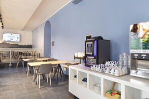 A modern cafe with a coffee machine, seating area, and a TV screen.