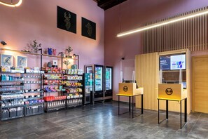 En hotellobby med en automat til snacks, forskellige varer på hylder og en salgsautomat.